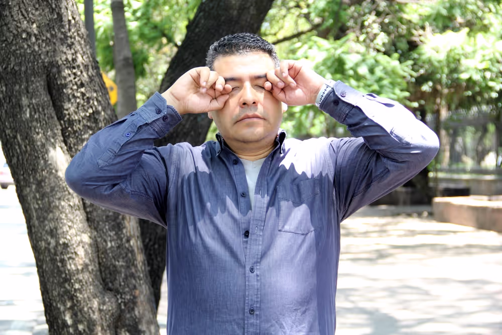 Hombre al aire libre frotándose los ojos